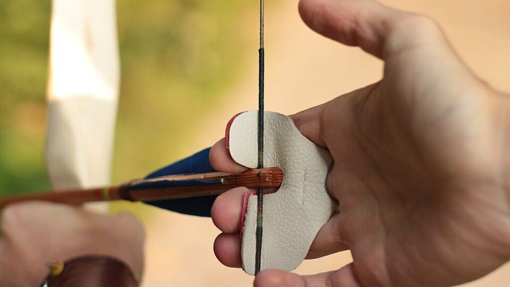 Hand mit Fingertab zieht die Sehne eines Bogens aus