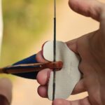 Hand mit Fingertab zieht die Sehne eines Bogens aus