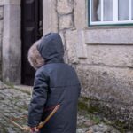 Kleines Kind mit Spielzeugbogen in einer Gasse