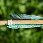 Grüne Naturfedern an einem traditionellen Holzpfeil